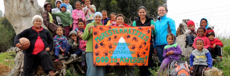 Die kleuters en personeel van Môresterretjies Pre-School by hulle Kilimanjaro-plakkaat, met regs van die plakkaat vlnr Sandra Wessels en Melinda du Plessis wat Kilimanjaro vir ‘n fondsinsamelingsprojek gaan uitklim